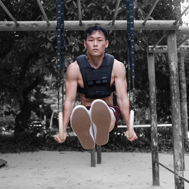 man wearing grav weighted vest doing l-sit on grav gymnastic rings